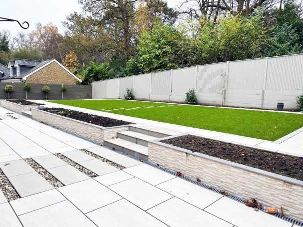 Modern garden design with grass, stone pathways, and raised planting beds.