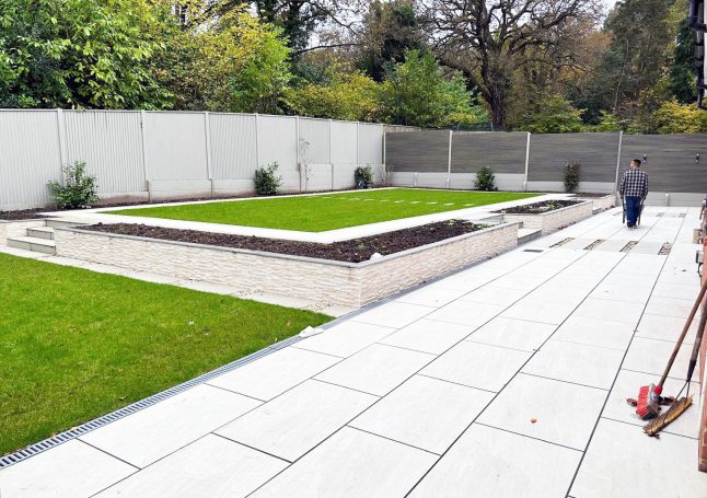 A landscaped garden with a pathway, lawn, and raised planting beds.